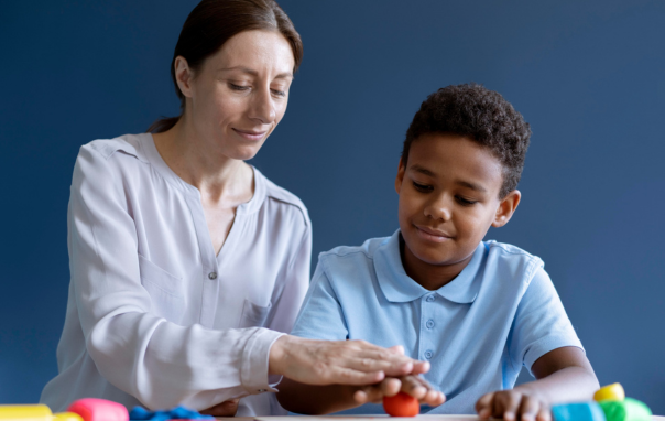 An early childhood assistant working with a boy